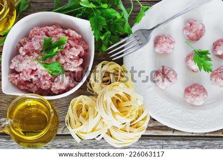 minced meat in a bowl and the ingredients for making pasta dishes on the old wooden table. european cuisine