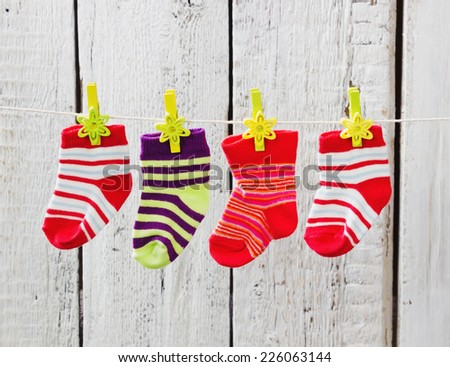 children\'s striped socks hanging from a rope on a white wooden background. children\'s clothing.