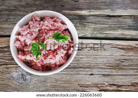 minced meat in a white bowl on the old wooden background. semi finished meat
