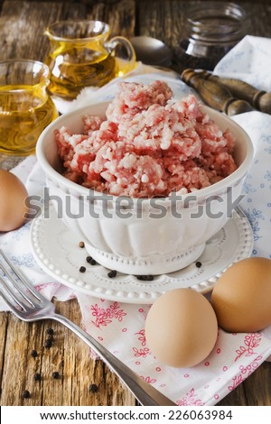 minced meat in a bowl and different ingredients on an old wooden table. meat dishes