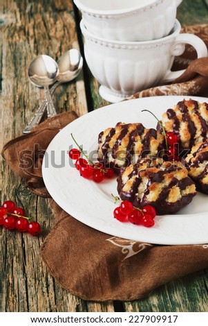 cookies poured chocolate and red currant berries in a plate on old wooden table.sweet breakfast