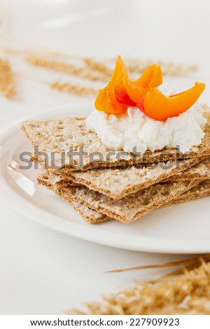 dried bread with cottage cheese and slices of apricot on a plate. health and diet food