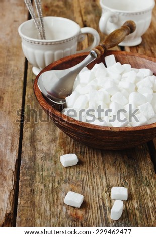 cubes of white sugar in a wooden bowl on old wooden table
