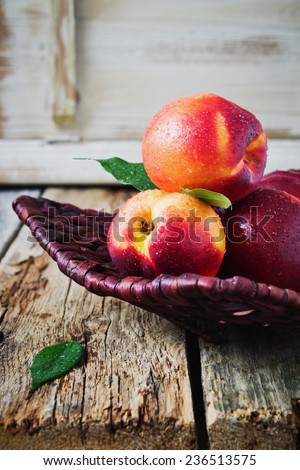 delicious ripe nectarine with water drops in a wicker plate on old wooden table.health and diet food