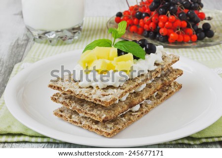rye bread with cottage cheese ,mango and berries of mountain ash on a white wooden background. healthy breakfast. selective focus. health and diet food