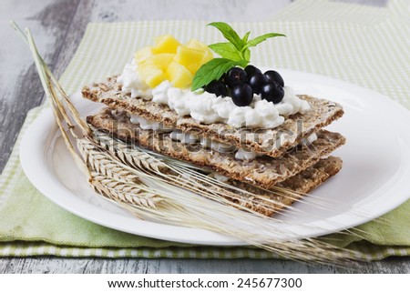rye bread with cottage cheese, black berries of mountain ash and mango on a white wooden background. healthy breakfast.