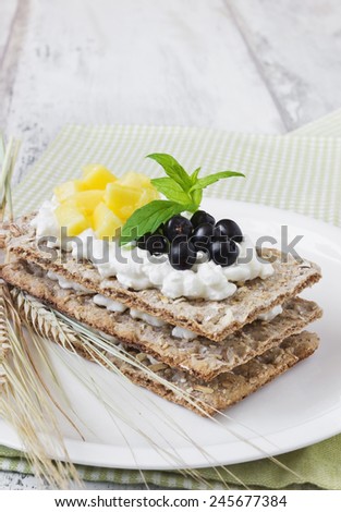 rye bread with cottage cheese, black berries of mountain ash and mango on a white wooden background. healthy breakfast. health and diet food
