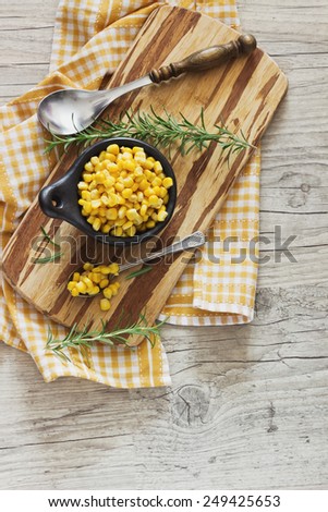 marinated corn in a bowl on a cutting board and rosemary on a wooden background. home preservation. top view.