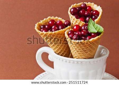 ripe cranberries in a waffle cone and vintage dishes on a brown background.health and diet food