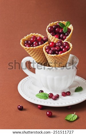 ripe cranberries in a waffle cone and vintage dishes on a brown background.health and diet food