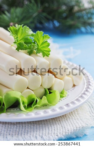 cheese sticks and lettuce on a plate on the table. cheese and dairy products. selective focus