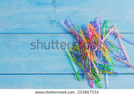 multicolored plastic sword sticks for canapes on a blue wooden background.copy space background