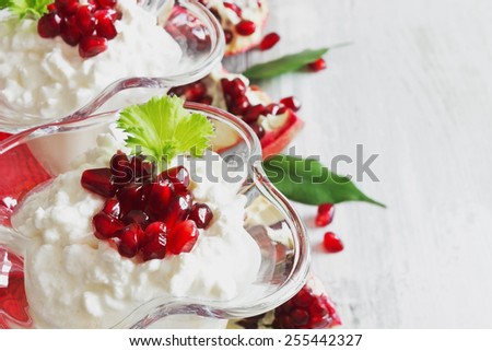 cottage cheese dessert with ripe pomegranate seeds in a beautiful ice-cream bowls on the table. close-up. healthy breakfast.