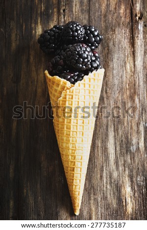 ripe blackberries in waffle cone on the old wooden background. top view. health and diet food
