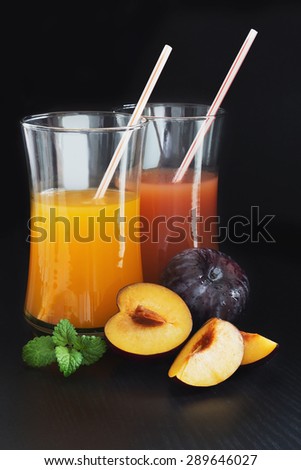 plum juice in a glass and fresh ripe plums on a black background.health and diet food
