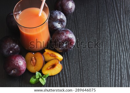 plum juice in a glass and fresh ripe plums on a black background.health and diet food. copy space  background