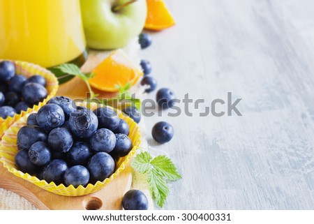 ripe blueberries in a paper cup and various ripe fruit.health and diet concept. copy space background. selective focus