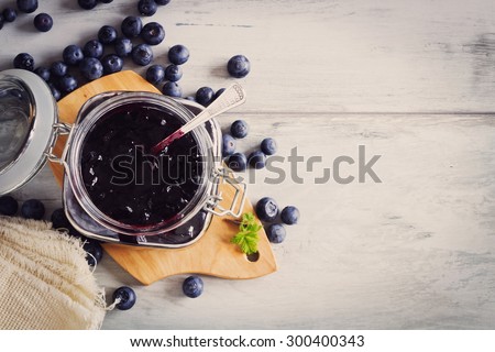 homemade blueberry jam in a jar and fresh blueberries on a table. toning vintage style. copy space background. top view