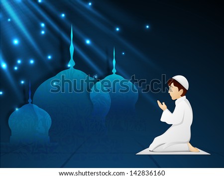 Little Muslim boy in traditional dress praying (reading Namaz, Islamic Prayer) with shiny view of mosque on blue background.