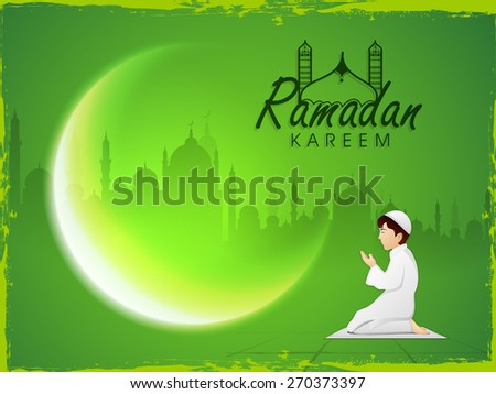 Cute Muslim boy reading Namaz (Islamic Prayer) and beautiful crescent moon on mosque silhouette background for Ramadan Kareem celebration.