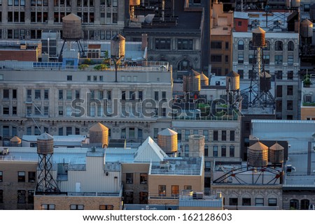 Late afternoon light over Chelsea building rooftops illuminating New York City typical water towers. Urban view of Manhattan rooftops.