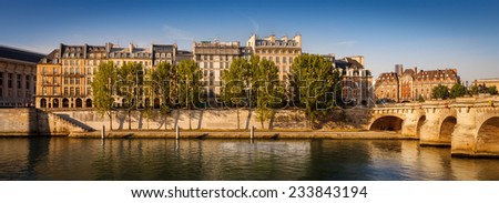 Warm morning sun rays falling on Pont Neuf, the residential buildings on Ile de la Cite and the aspens lining the River Seine bank, Paris. Dawn in France\'s capital city, the City of Lights.
