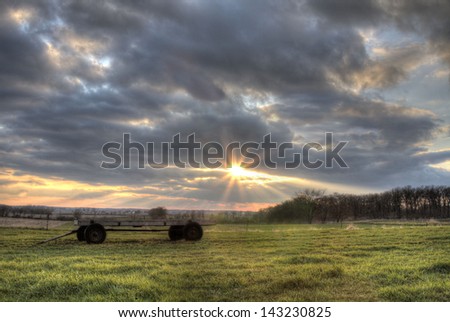 A wagon in a sunset in a field of grass.