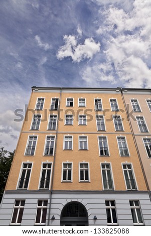 Low and wide angle view of an apartment building under cloudy Berlin sky.