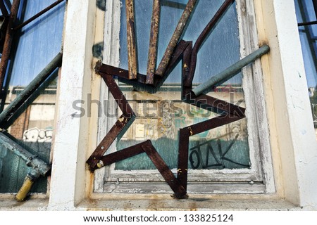 BERLIN-CIRCA 2013: Low and wide angle view of an abandoned building\'s windows and bars artistically made out of old industrial metal pieces and made to a star shape. RAW tempel, Friedrichshain, Berlin.
