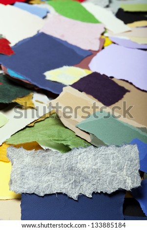 Torn long white rice fiber paper on the background of a large group of torn pieces of paper in a variety of colors. Good as copy space for text.