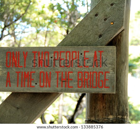 A sign at the entrance of a rope bridge indicating that it is safe for a maximum of two persons at a time to be on it