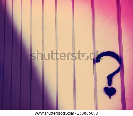 An abstract cross process image of a wall with a spray painted heart under a question mark.