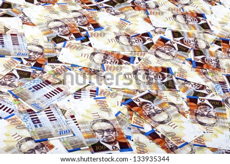 A high angle view of a very large amount of 100 NIS (New Israeli Shekel) money notes spreaded in a messy manner.