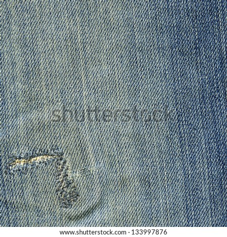 High resolution scan of blue denim fabric with a large stitch-fixed rip and a general worn-out look. Scanned at 2400dpi using a professional Epson V700 scanner.