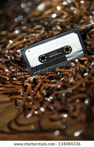 Black recordable plastic audio cassette resting on a large amount of magnetic audio tape. Selective focus on foreground.