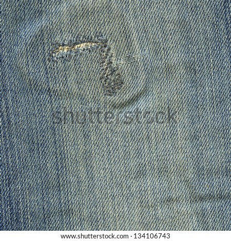 High resolution scan of blue denim fabric with a large stitch-fixed rip and a general worn-out look.