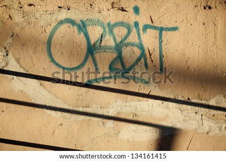 A graffiti tag \'orbit\' on an urban wall. Shot in the early morning.