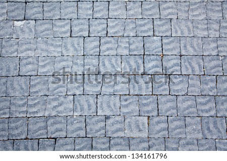 Gray floor tiles with wavy/rippled texture lit by diffused afternoon sun. Good as background.