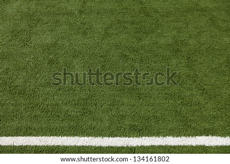 Artificial lawn with a white stripe painted on it. Part of a sports field.