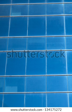 Dark blue office building\'s curtain wall made of square windows.