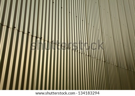 Golden metal squiggly wall in the sunlight. Depicted diagonally.