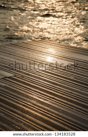 A wooden deck completely soaked wet by the waves of the gushing sea hitting against it on a winter day.