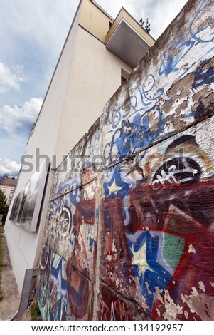 BERLIN - JUNE 10th: Graffiti covered remains of the Berlin wall in Bernauer strasse. The photos on the building depict the changes throughout the years, on June 10th, 2012, in Berlin, Germany.