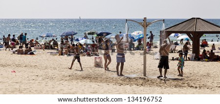 TEL AVIV - AUGUST 18th: The beach in Tel Aviv, packed with people on a hot summer day. Some are in the water, some are sunbathing or shade dwelling, and the shower is working in full power, on August 18th 2012, in Tel Aviv, Israel.