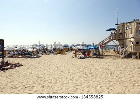 TEL AVIV - AUGUST 18: View looking west at the Tel Aviv beach on a summer day, busy with  people sunbathing or hiding in the shade on August 18 2012 in Tel Aviv, Israel.