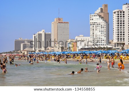 TEL AVIV - AUGUST 18: Beach and hotels strip packed with several people sunbathing, hiding in a parasol\'s shade, or cooling themselves in the ocean. On August 18 2012 in Tel Aviv, Israel.