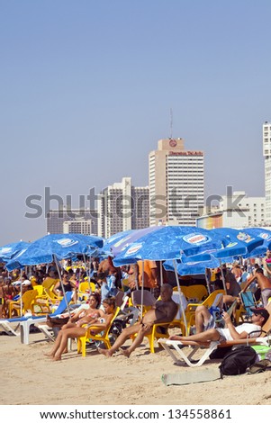 TEL AVIV - AUGUST 18: The Tel Aviv beach and hotels strip, packed with several people either sunbathing or hiding in a parasol\'s shade. On August 18 2012 in Tel Aviv, Israel.