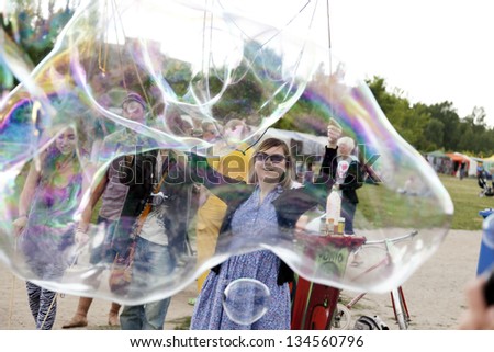 BERLIN - JUNE 10: A group of young adults making giant soap bubbles on an early summer day at Mauerpark, with the flea market in the backgroundon June 10 2012 in Berlin, Germany.