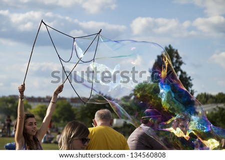 BERLIN - JUNE 10: A young unidentified woman making giant soap bubbles on an early summer day at Mauerpark, with a crowd surrounding on June 10 2012 in Berlin, Germany.