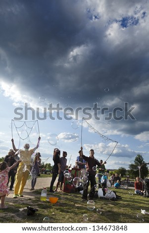 BERLIN - JUN 10: A group of people making giant soap bubbles on a summer day at Mauerpark, with the park\'s crowd surrounding them. On June 10 2012 in Berlin, Germany.
